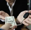 Manos de hombres intercambiando dinero y llaves de carro haciendo alusión al préstamo con garantía de auto