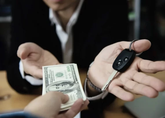 Manos de hombres intercambiando dinero y llaves de carro haciendo alusión al préstamo con garantía de auto