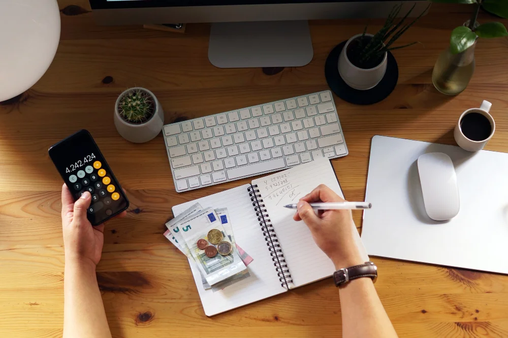 Manos de persona escribiendo en cuaderno calculando la tasa de interés promedio para préstamos personales